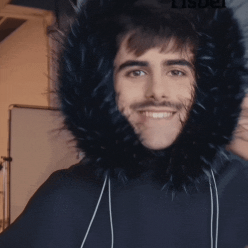 a man wearing a black furry hood giving a thumbs up