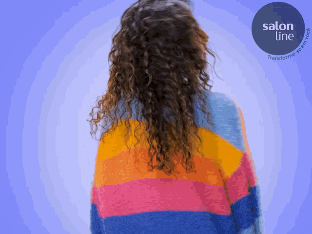a woman with curly hair is wearing a colorful sweater with salon line written on the bottom