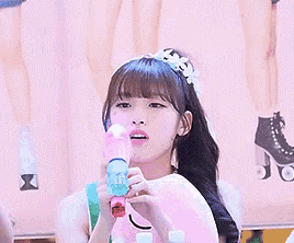 a girl wearing a flower headband is holding a pink dolphin toy in her hands .