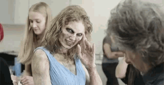 a woman with a zombie makeup on her face is waving at a man in a room .