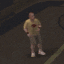 a blurry picture of a man in a yellow shirt and shorts standing on a basketball court .