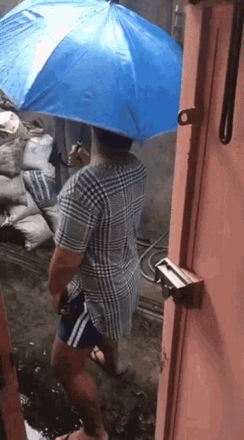 a person holding a blue umbrella standing in the rain