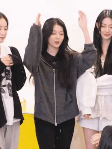 a girl wearing a grey adidas jacket stands in front of two other girls
