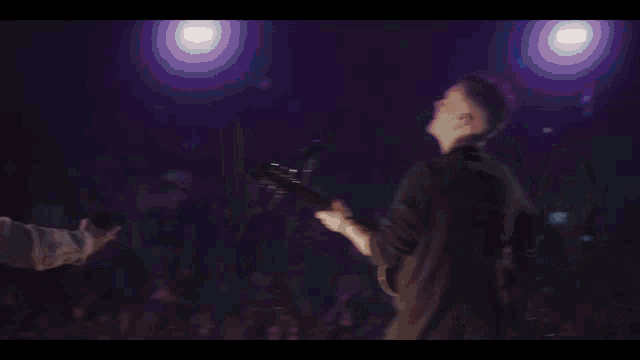 a woman is singing into a microphone in front of a crowd of people
