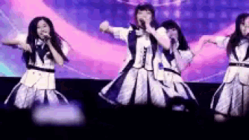 a group of girls are standing on a stage holding microphones .