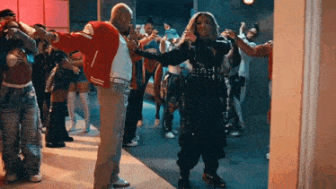 a man in a red jacket is dancing with a woman in a black outfit .