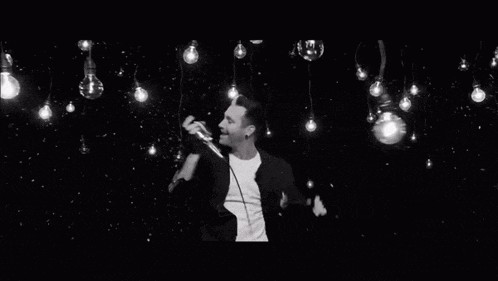 a man is singing into a microphone in a black and white photo