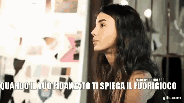 a woman is sitting in front of a wall with the words quando il tuo fidanzato ti spiega il fuorigioco written on it