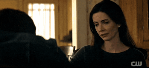 a woman in a dark room with a cw logo on the bottom right