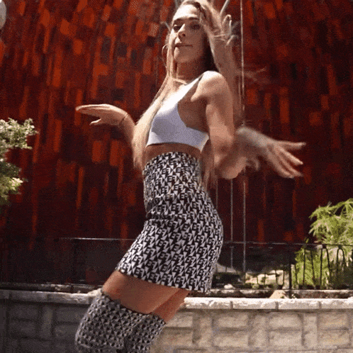 a woman in a white top and black and white skirt dancing