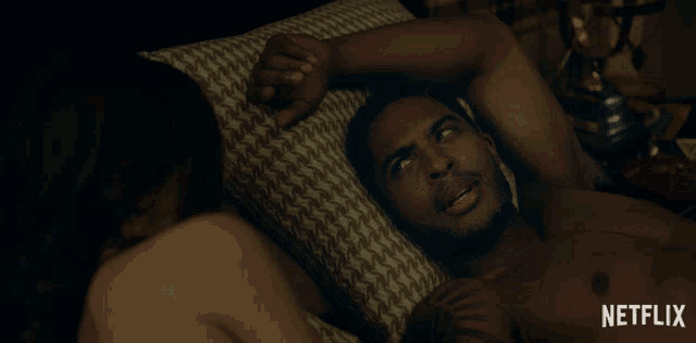 a man laying on a bed next to a woman with a netflix logo on the bottom right