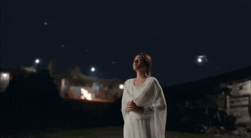 a woman in a white dress is looking up at the sky