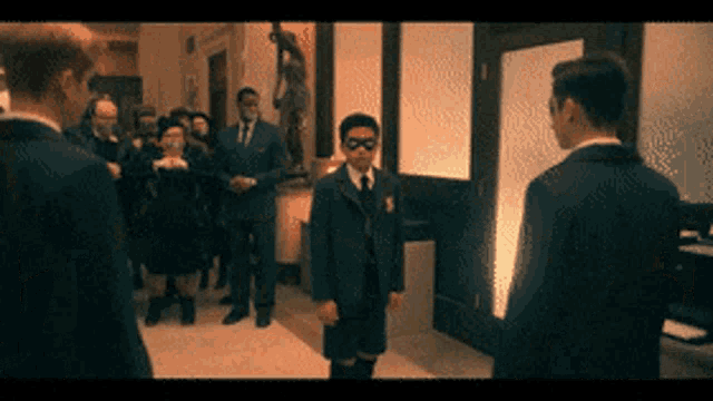 a man in a suit and tie stands in front of a group of men