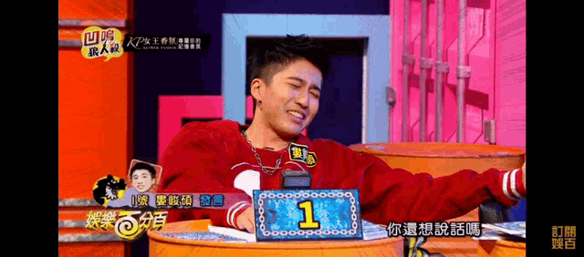 a man sitting at a table with a sign that says 1
