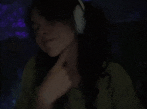 a woman wearing headphones is sitting on a couch in a dark room .