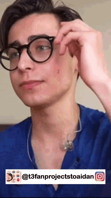 a young man wearing glasses and a blue shirt has a sticker on his face that says t3fanprojecttoaidan