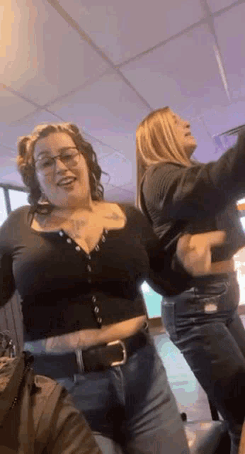 two women are standing next to each other in a room dancing .