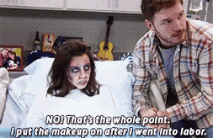 a man is standing next to a woman in a hospital bed who is wearing makeup .