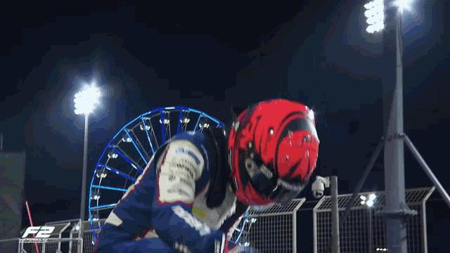 a man wearing a red helmet and a blue and white suit is jumping in the air