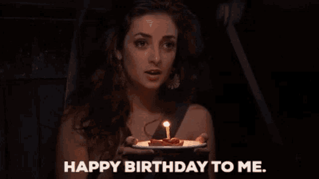 a woman is blowing out a candle on her birthday cake and saying happy birthday to me .