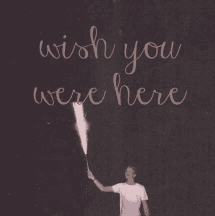 a man is holding a fireworks display in front of a sign that says wish you were here