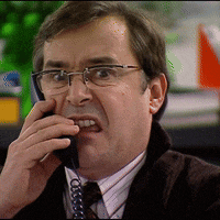 a man wearing glasses and a tie is talking on a phone