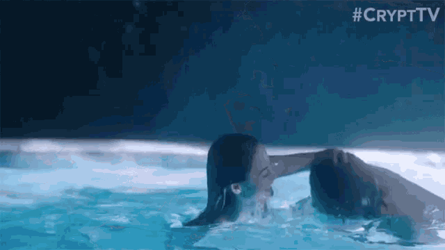 a man and woman are kissing in a pool .