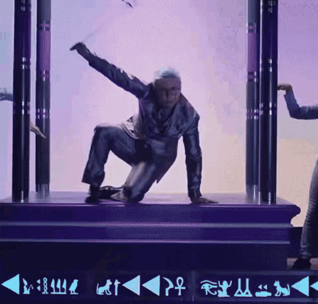a man in a suit is kneeling down on a stage with a sign that says ' egyptian ' on it