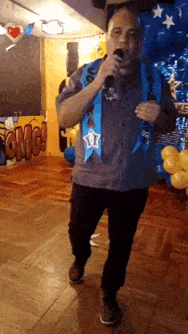 a man is singing into a microphone in front of balloons and a sign that says omg