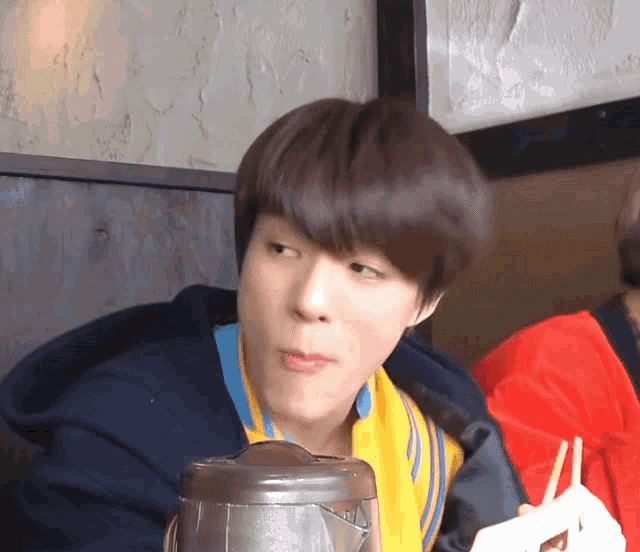 a close up of a person eating with chopsticks and a container