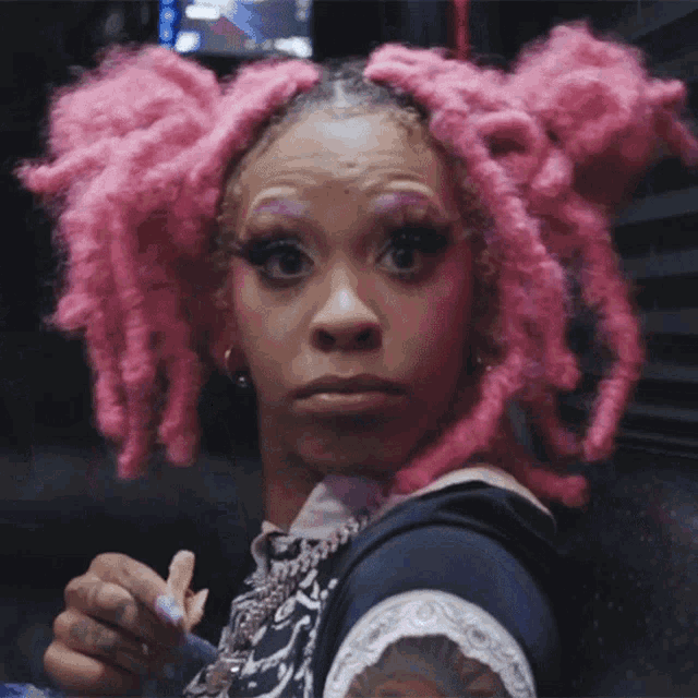 a woman with pink dreadlocks has a tattoo on her arm