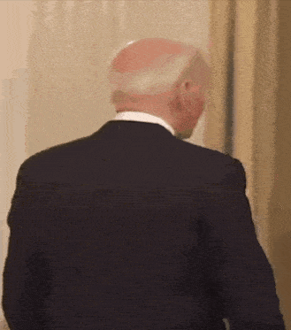 the back of a bald man in a suit and white shirt is shown .