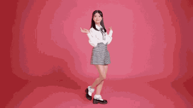 a girl in a white shirt and shorts is dancing in front of a pink background