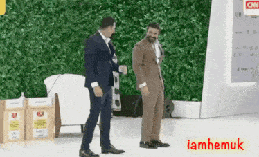two men in suits are standing in front of a wall with cnn written on it