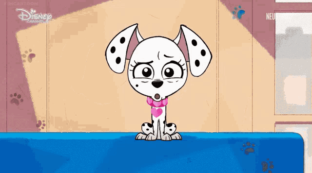 a dalmatian dog is sitting on a blue blanket with disney written on the bottom
