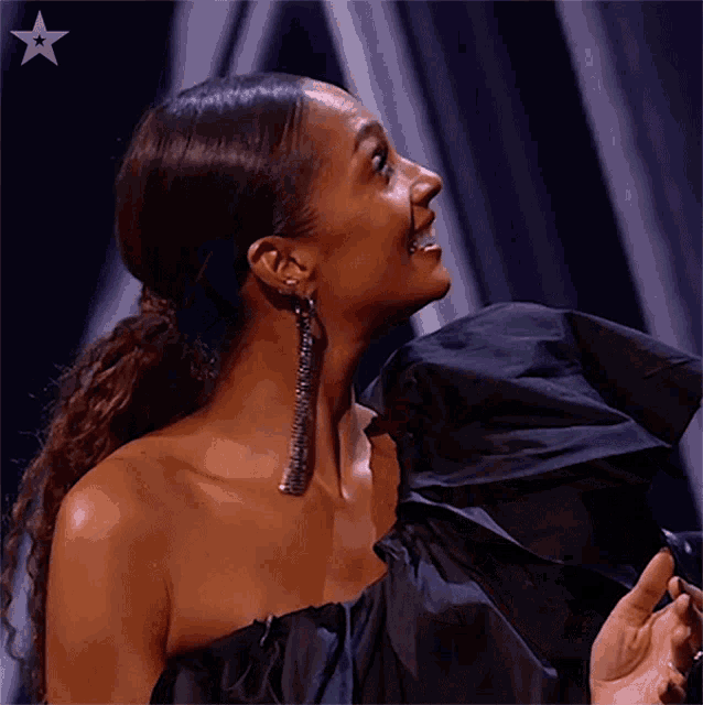 a woman in a black dress with a silver star on her chest