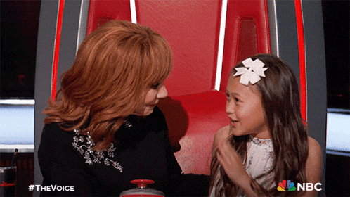 a woman and a little girl are sitting next to each other in a chair with a nbc logo behind them