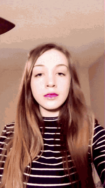 a girl with long hair wearing a black and white striped shirt has purple lipstick on her lips