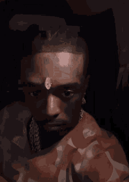 a close up of a man 's face with a diamond on his forehead .