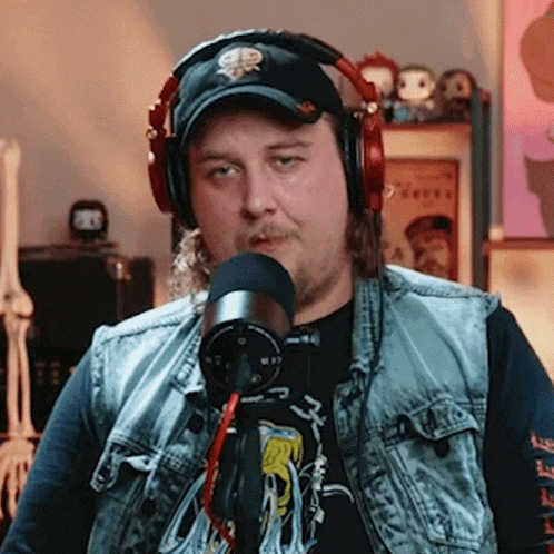 a man wearing headphones and a hat with a skull on it is talking into a microphone