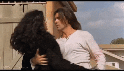 a man is holding a woman in his arms while they are kissing .