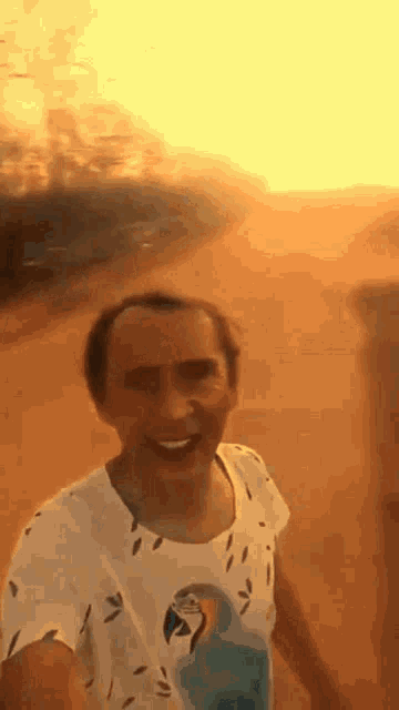 a man wearing a white shirt with a parrot on it is walking in the desert .