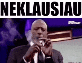 a man in a suit and tie is smoking a cigarette in front of a microphone with the word neklausiau written above him