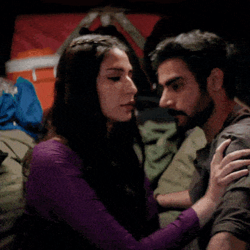 a man with a beard and a woman with braided hair are looking into each other 's eyes