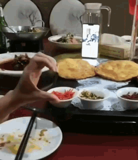 a person reaches for a plate of food while a cell phone is on the table