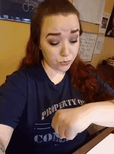 a woman wearing a blue shirt that says property on it looks at her watch
