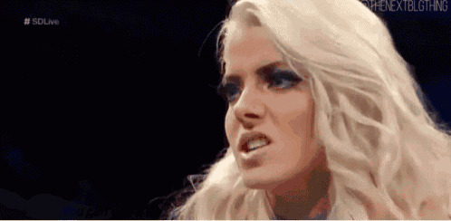 a woman with blonde hair and blue eyes is making a funny face in a wrestling match .