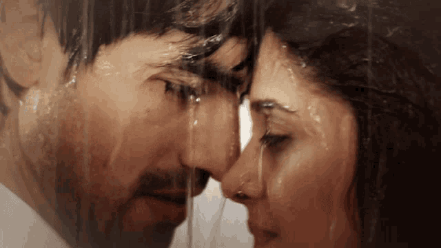 a man and a woman are looking into each other 's eyes in the rain