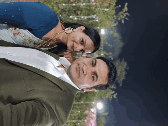a man in a suit and a woman in a blue dress pose for a picture