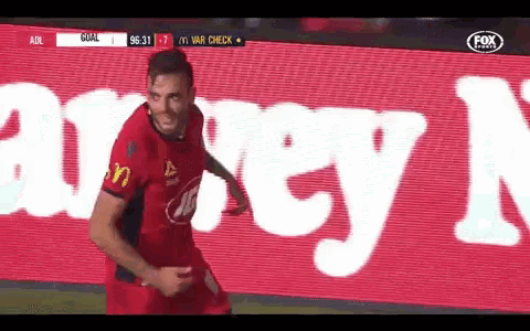 a soccer player celebrates a goal in front of an ad for fox